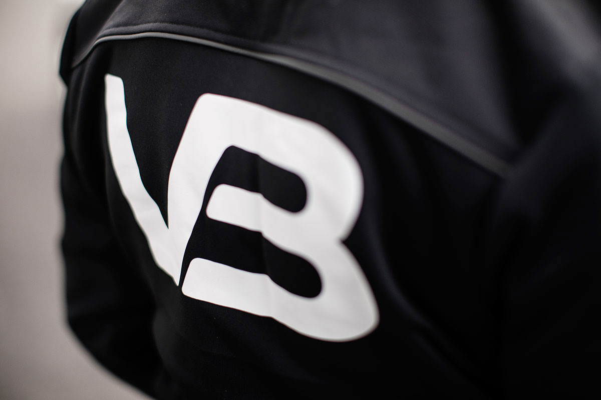Nærbilde av hvit VB-logo på svart tekstil.